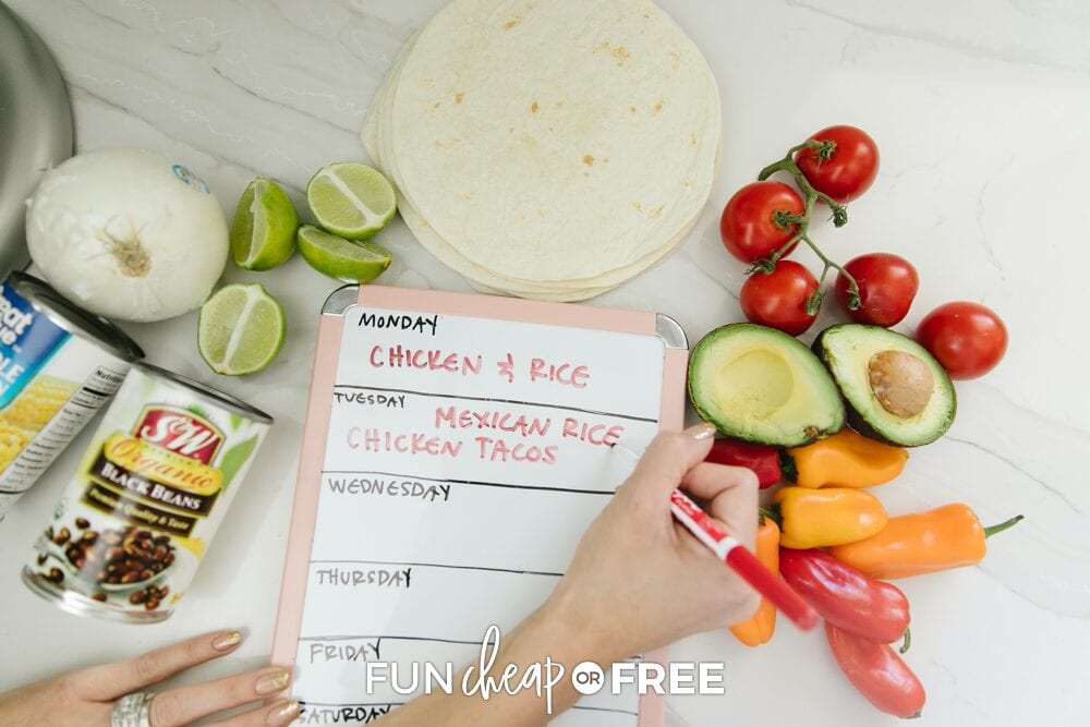 Writing down meal plan on a dry erase board surrounded by food, from Fun Cheap or Free