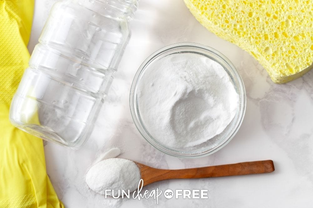 Bowl of baking soda and wooden spoon on marble counter top from Fun Cheap or Free. 