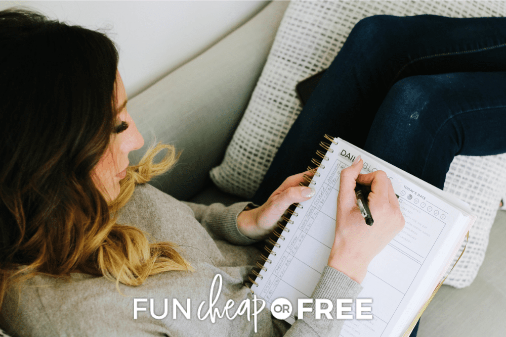 Image of Jordan Page sitting on a sofa. She is writing in a block schedule planner to organize kids' activities. - Fun Cheap Or Free